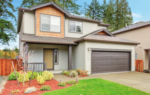 A beautiful home with landscaping and a brown garage door.