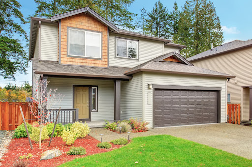 A beautiful home with landscaping and a brown garage door.